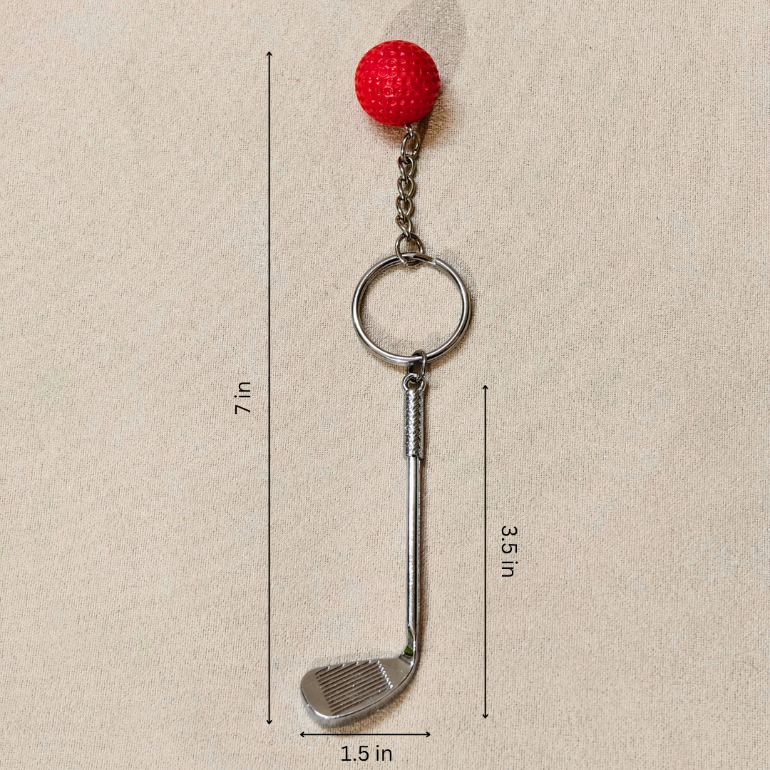 A golf club-shaped keychain with a red textured ball on top, shown on a beige background with dimension lines and labels indicating 7 in total height, 3.5 in shaft height, and 1.