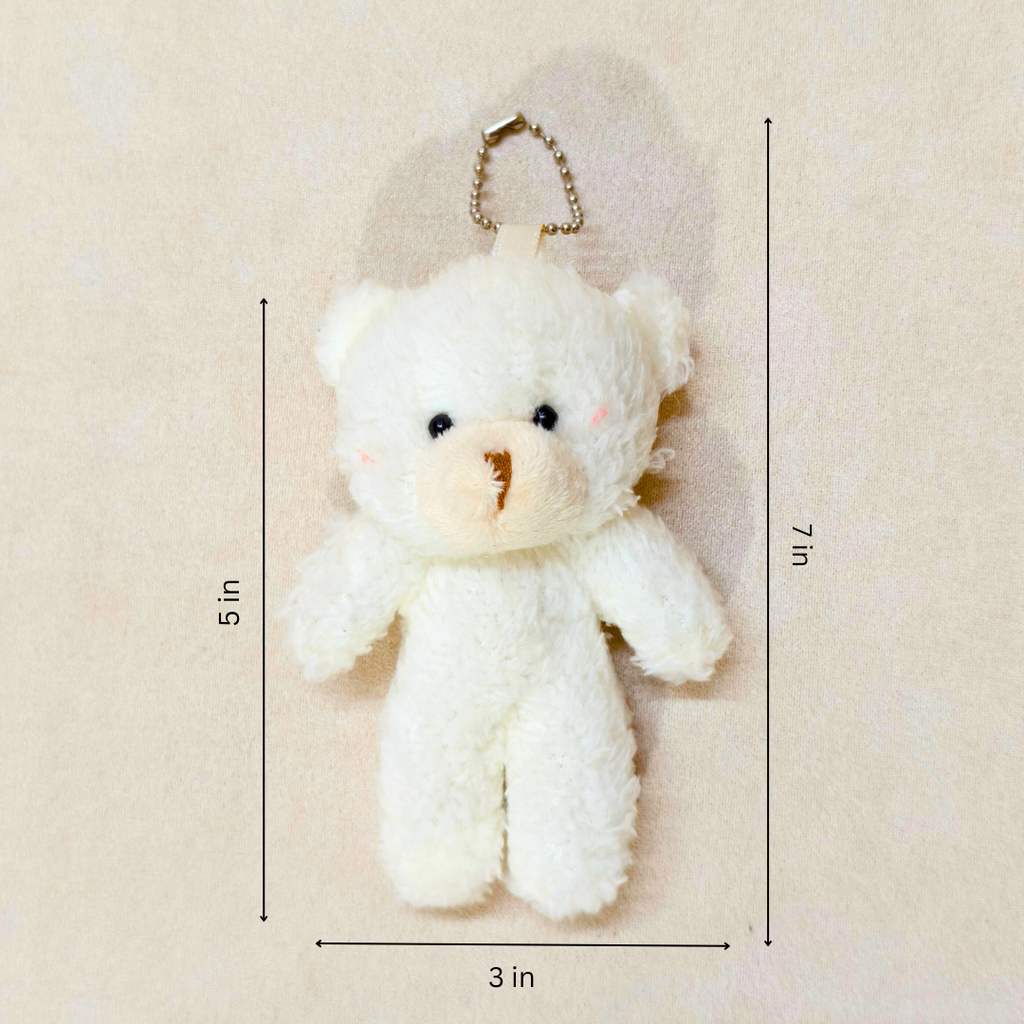 White teddy bear keychain with measurements on a beige background