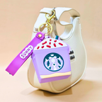 Starbucks-themed purple air pod case with a keychain on a beige background