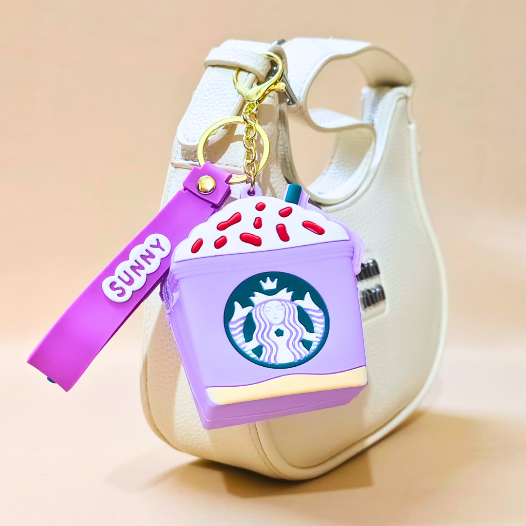 Starbucks-themed purple air pod case with a keychain on a beige background