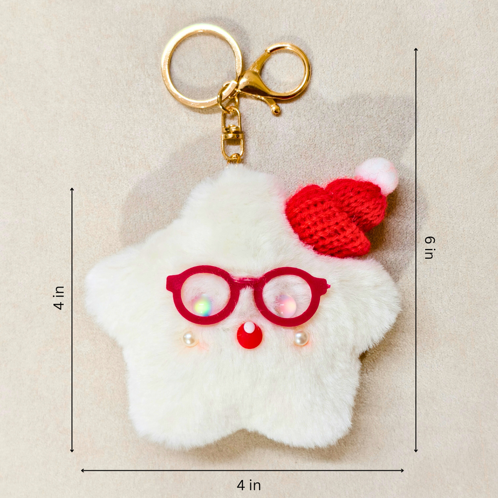 A white fluffy star-shaped keychain charm with red glasses, a red knit Santa hat, and a gold key ring, shown on a beige background with dimension lines indicating 4 in by 9 in.