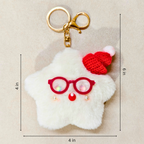 A white fluffy star-shaped keychain charm with red glasses, a red knit Santa hat, and a gold key ring, shown on a beige background with dimension lines indicating 4 in by 9 in.
