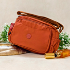  Rust Brown Sling Bag With Props In Front Of Beige Background.