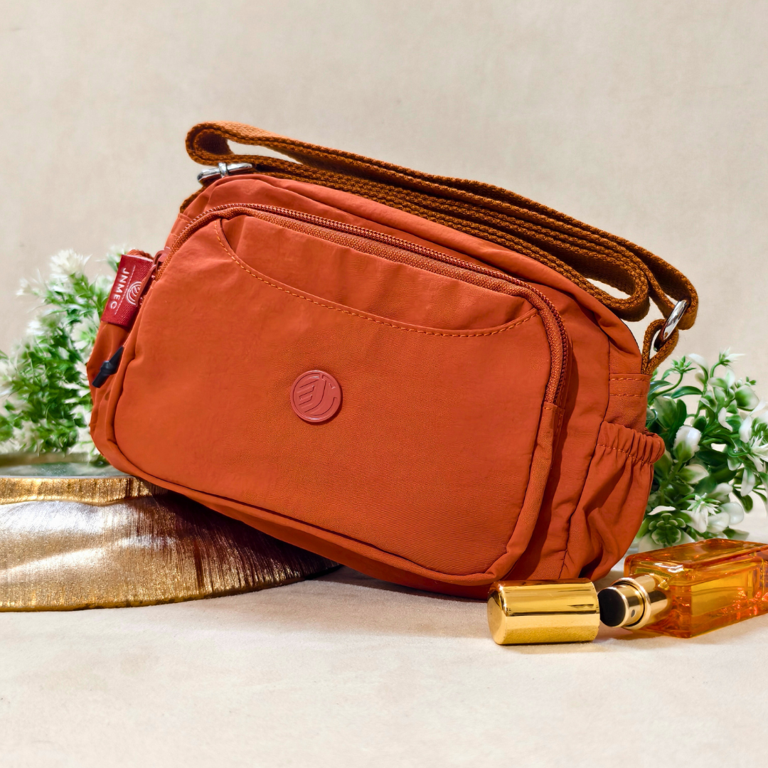  Rust Brown Sling Bag With Props In Front Of Beige Background.