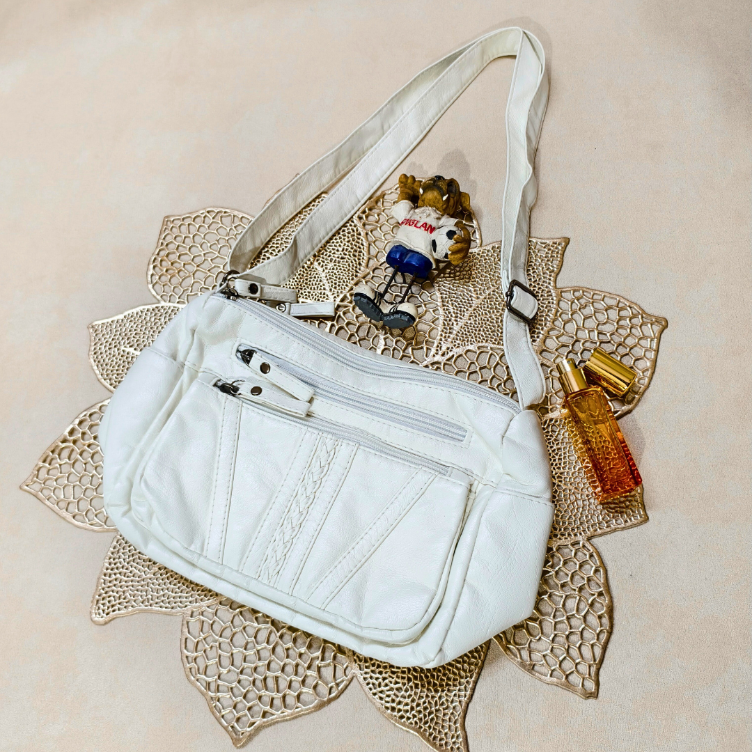 White handbag with a small plush toy and bottles on a decorative mat