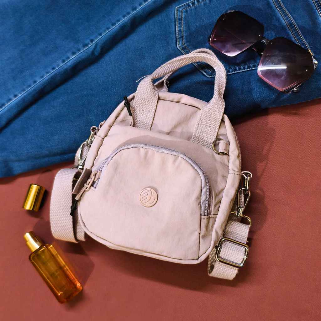 Beige backpack with sunglasses and bottles on a red surface