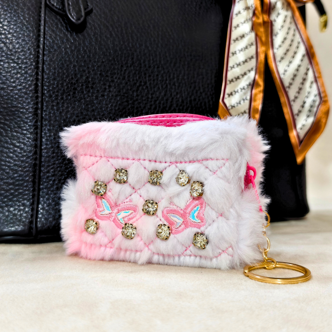 Small pink and white embellished pouch with a keychain on a neutral background