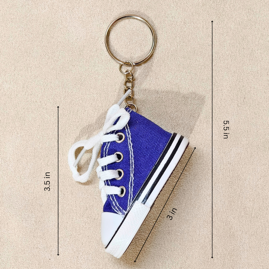 A miniature blue canvas sneaker keychain with white laces and a gold metal key ring, shown on a beige textured background with black dimension lines and text indicating its height of 3.5 in, length of 3 in, and overall height of 5.