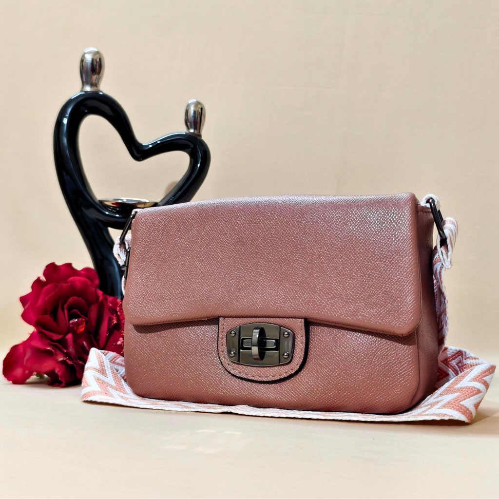 Pink handbag on a beige surface with a decorative heart and red flower in the background
