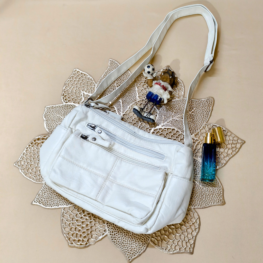 White handbag with a decorative strap on a textured beige surface