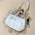 White handbag with a decorative strap on a textured beige surface