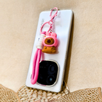 Phone case with a pink keychain on a beige background