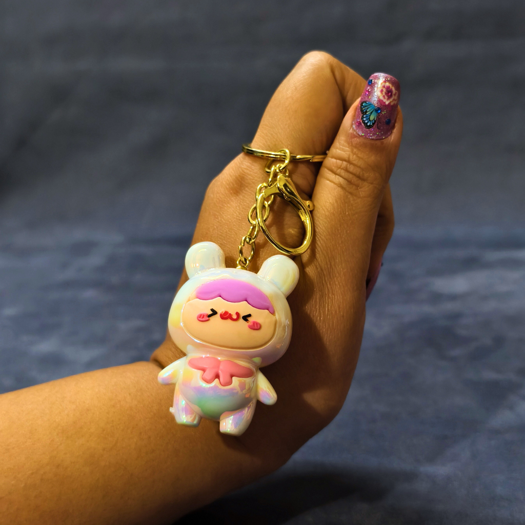 Hand holding a cartoon character keychain against a dark background