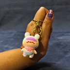 Hand holding a cartoon character keychain against a dark background