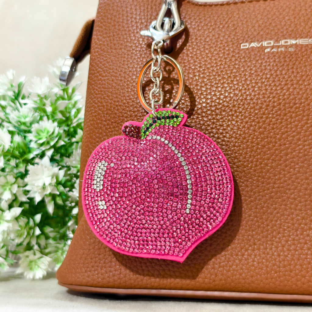 Pink pomegranate-shaped keychain on a brown handbag with 'DAVID JONES' branding.
