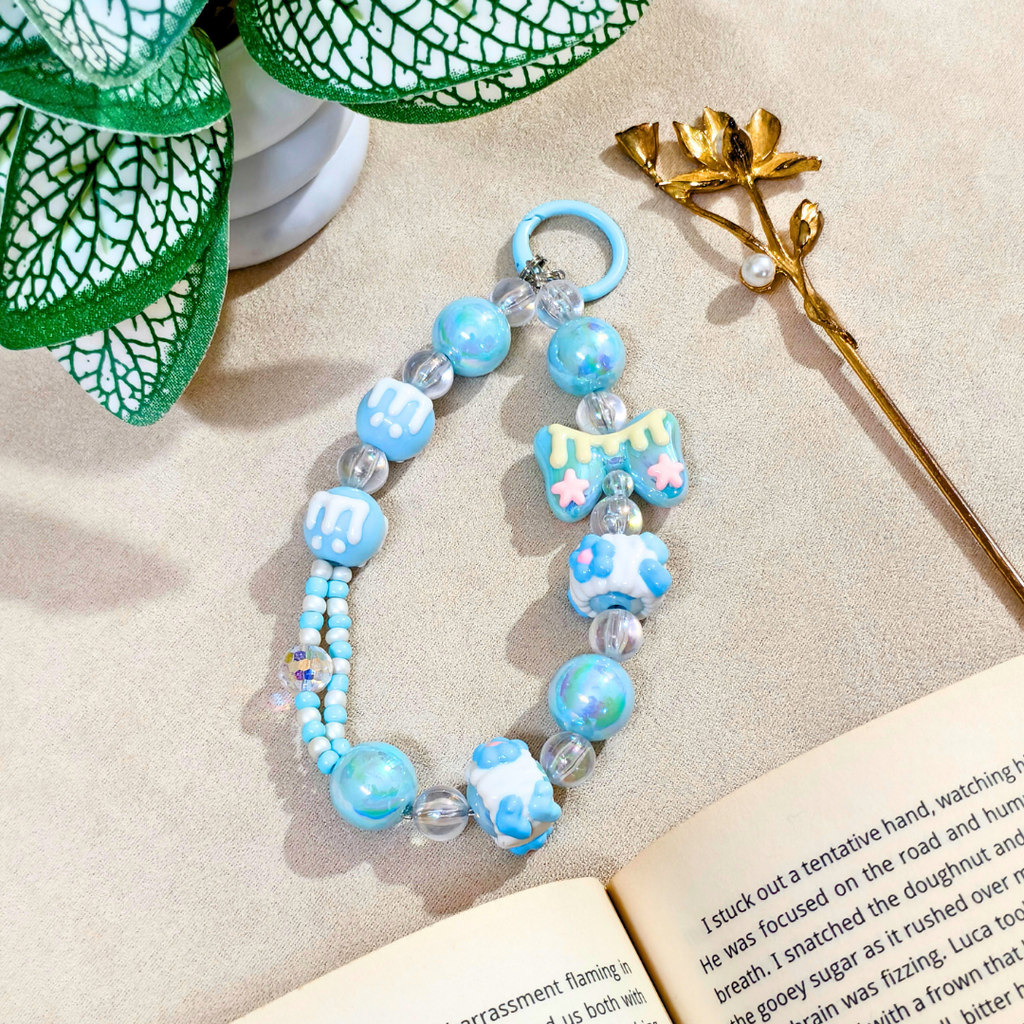Decorative blue beaded keychain on an open book with a plant in the background