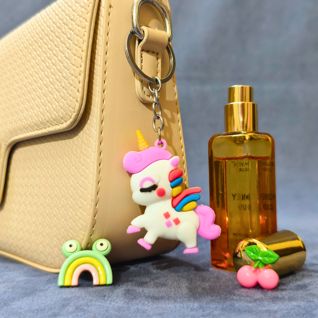 Unicorn keychain with a gold bottle and cherry charm on a textured surface