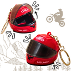 Two red motorcycle helmet keychains with gold-tone split rings, shown on a white background with simple line drawings of mountains, trees, and a motocross rider.