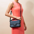 Woman holding a blue handbag against a beige background