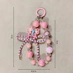 Pink beaded keychain with measurements on a beige background