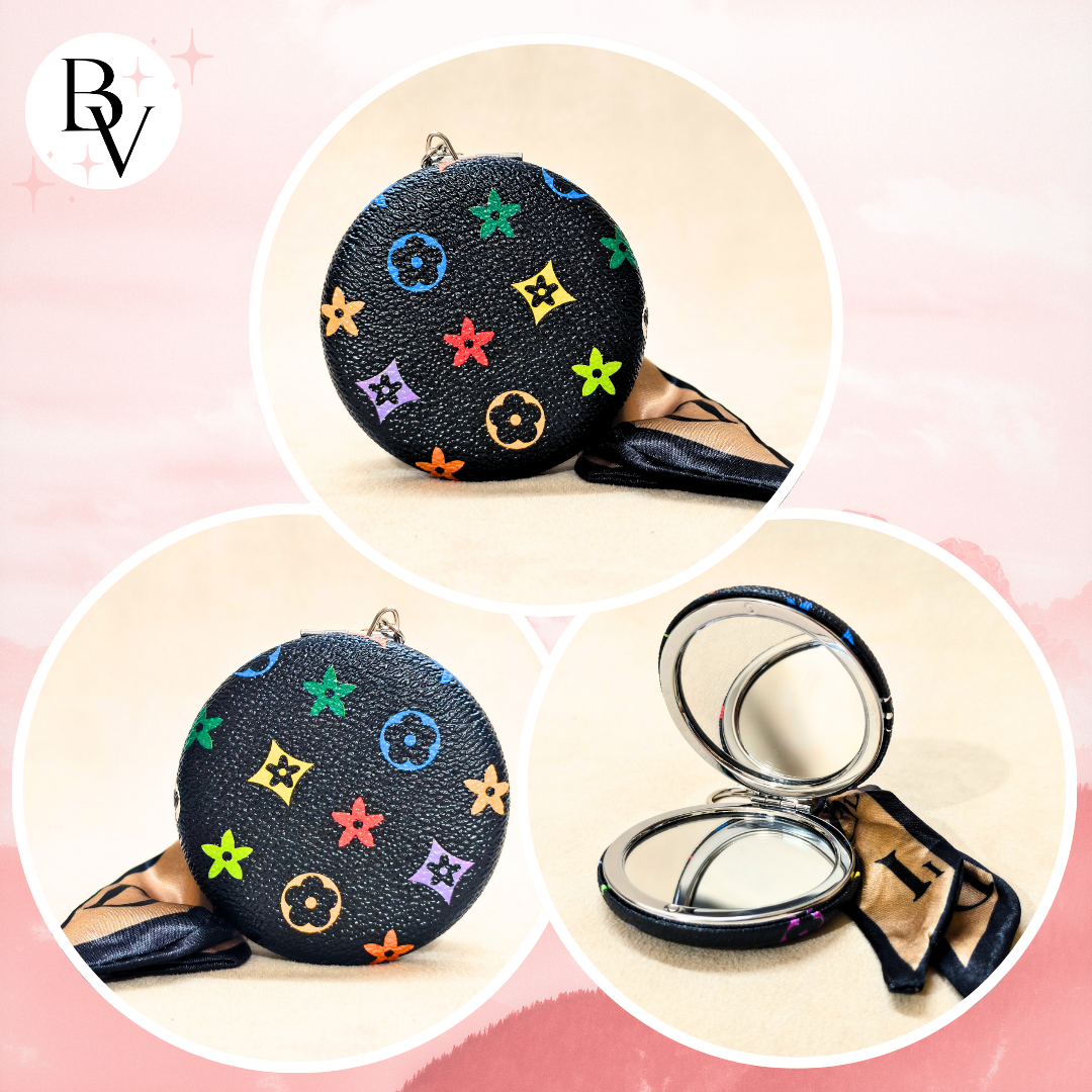A round black compact mirror with a colorful Louis Vuitton-style monogram pattern, shown in three circular views: closed, open with mirror visible, and open with a tan fabric pouch beside it. A stylized 'BV' logo appears in the top-left corner.