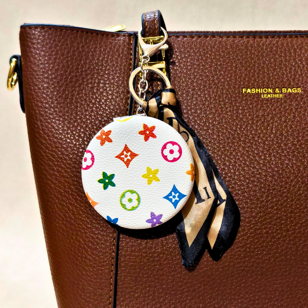 Round LV White Pocket Mirror Attached With Purse As  Bag Charm On  Beige Background.