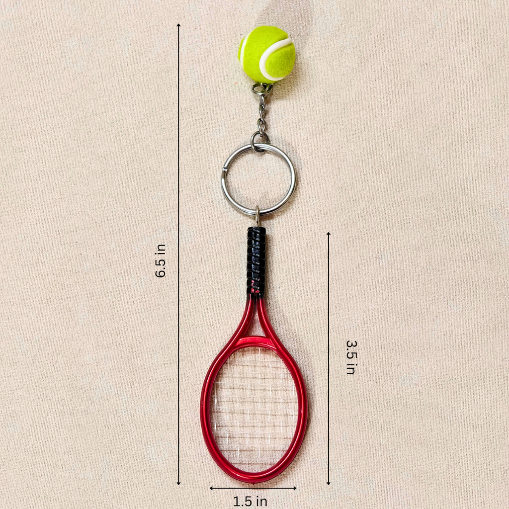 A novelty tennis racket keychain featuring a red tennis racket head with white strings, a black wrapped grip, a silver split ring, a short chain, and a small yellow-green tennis ball charm with white lines, shown on a beige background with measurements.