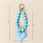 Blue beaded keychain with a heart-shaped pendant on a beige background