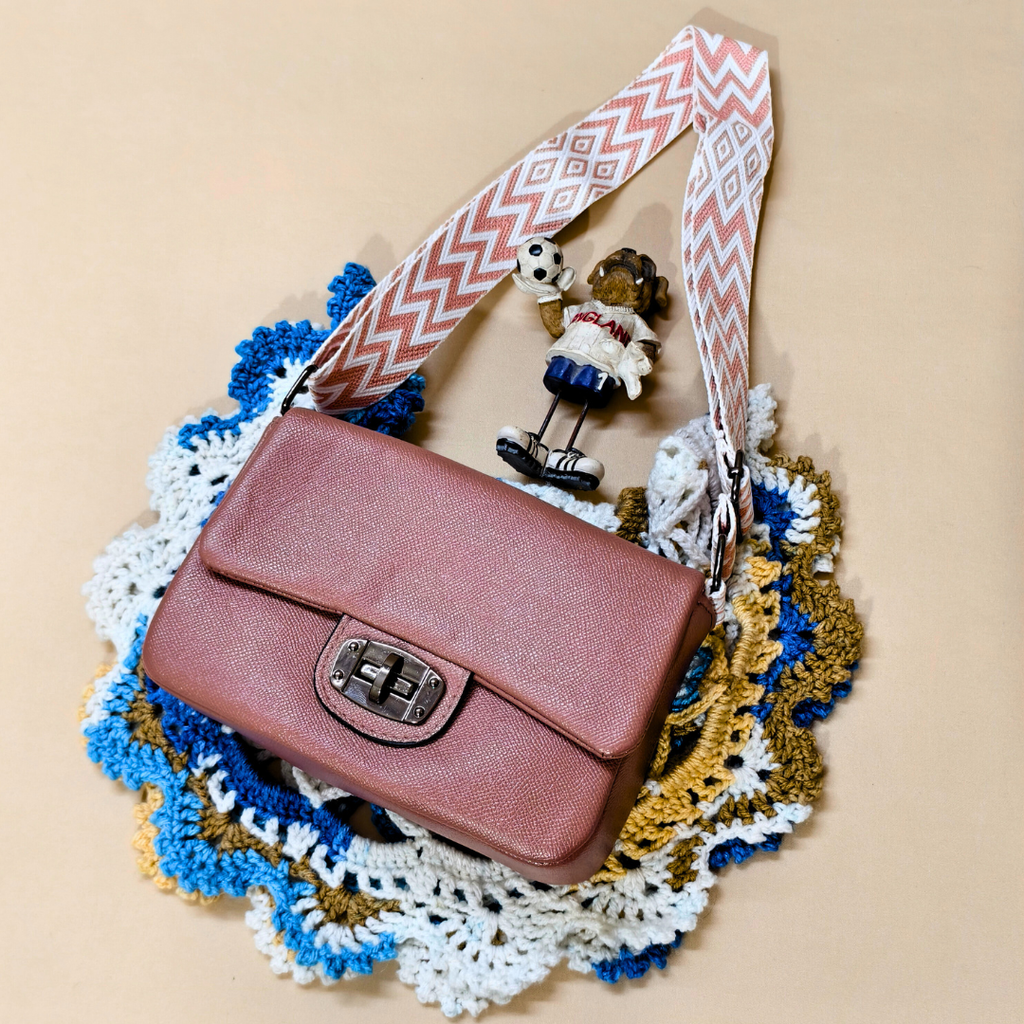 Pink handbag with a colorful strap on a textured surface