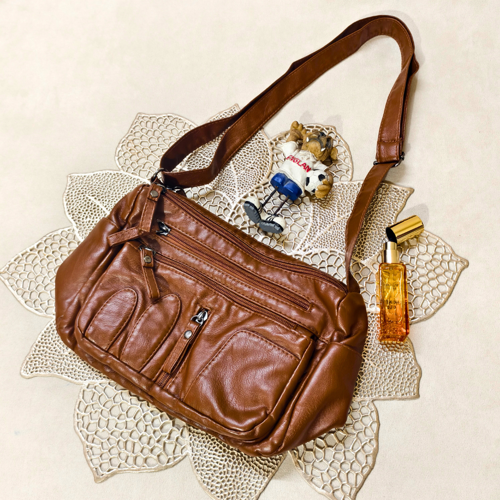 Brown leather bag on a textured surface with a small toy and bottle.