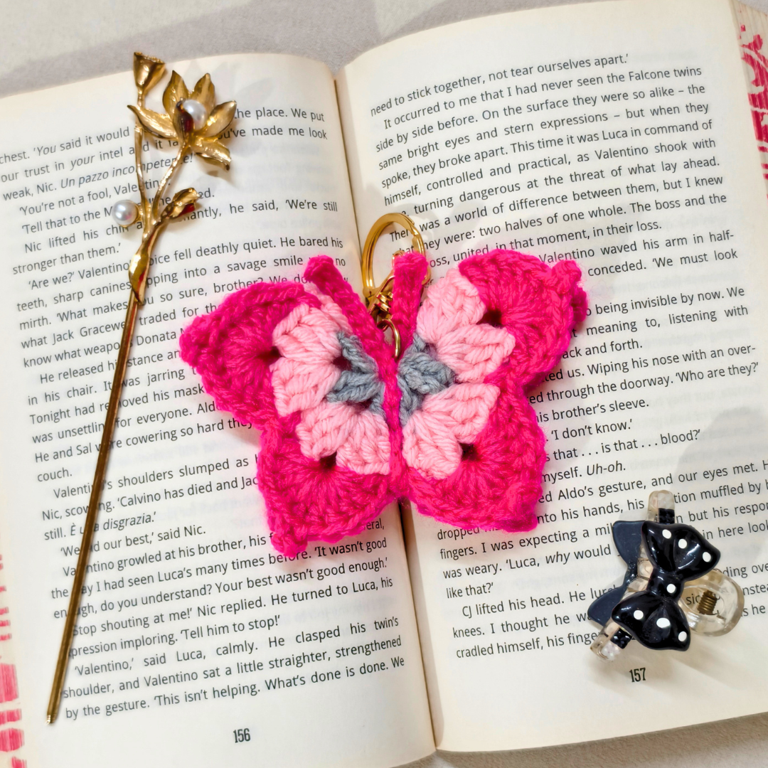 Pink butterfly-shaped crochet keychain on an open book