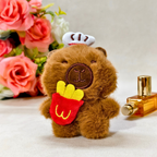 Plush toy bear with a chef hat and French fries, next to a perfume bottle and flowers on a light background