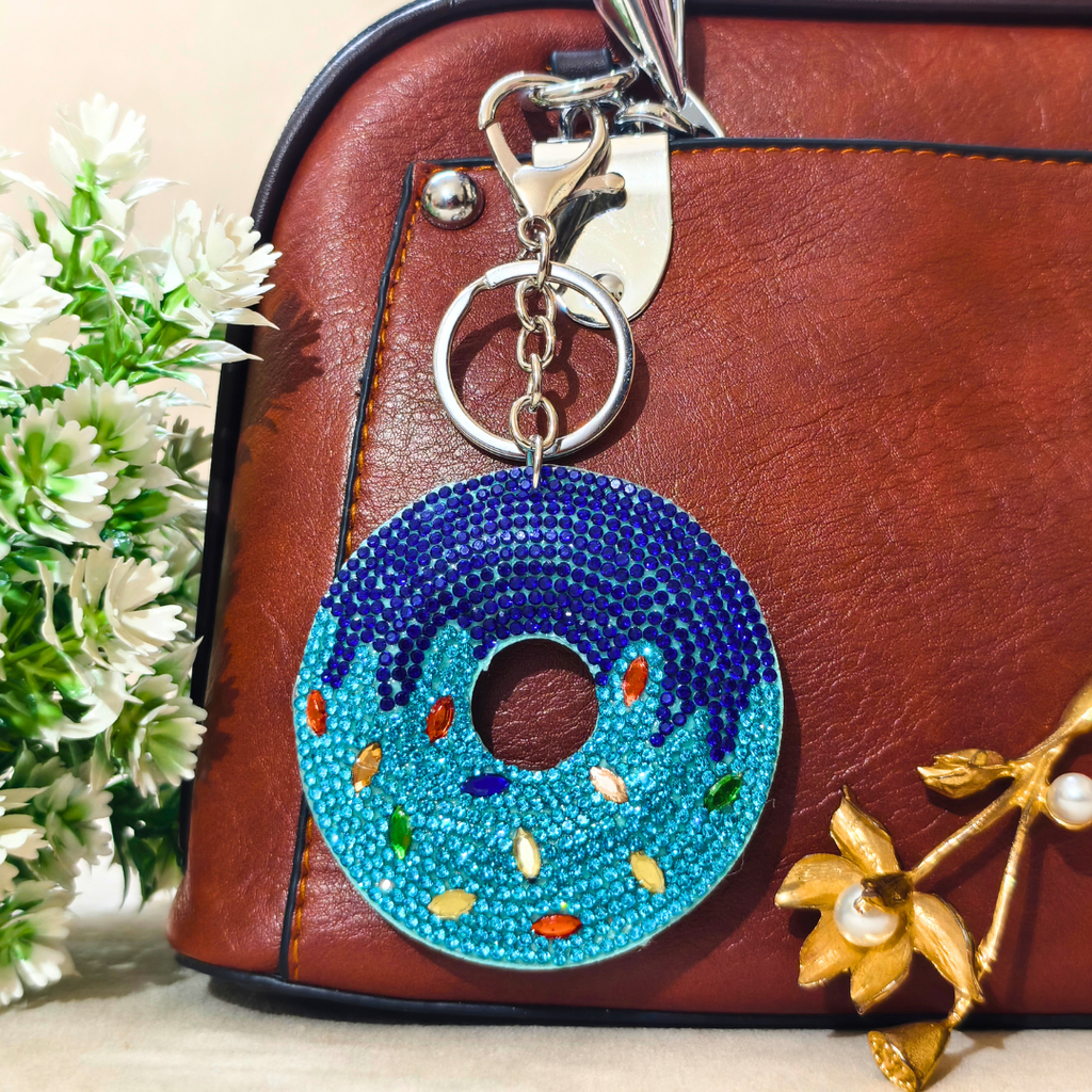 Decorative keychain on a brown leather bag with flowers in the background
