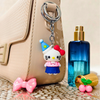 Cartoon character keychain on a beige handbag with a blue bottle and pink bow in the background.