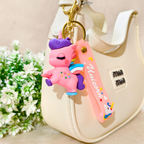 Pink cartoon character keychain with a knife attached to a beige handbag with flowers in the background.