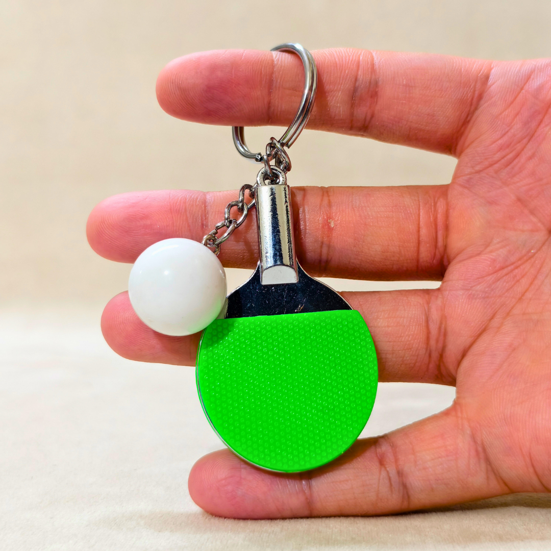 Sporty Table tennis Keyring Attached with silver chain and ring along with white ball holding in hand on beige background.