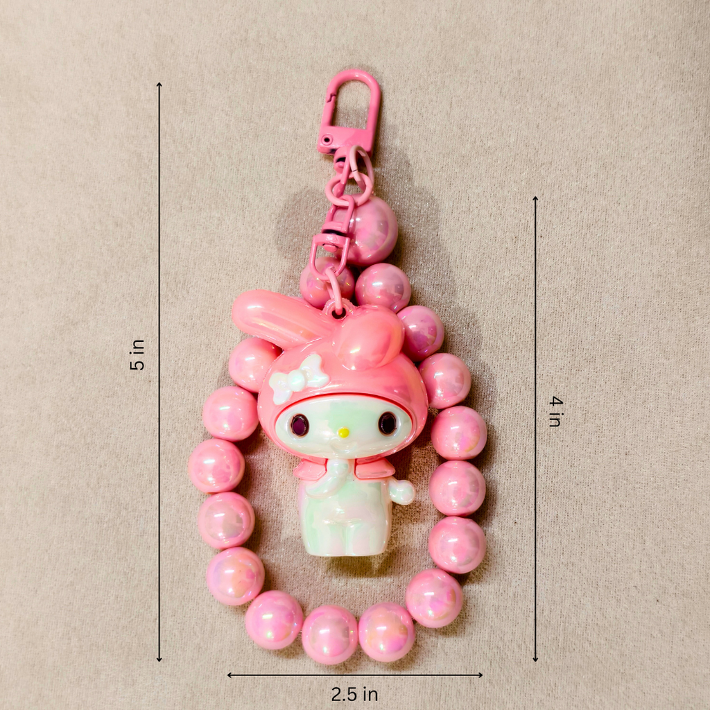 Pink character keychain with measurements on a beige background