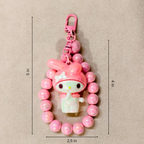 Pink character keychain with measurements on a beige background
