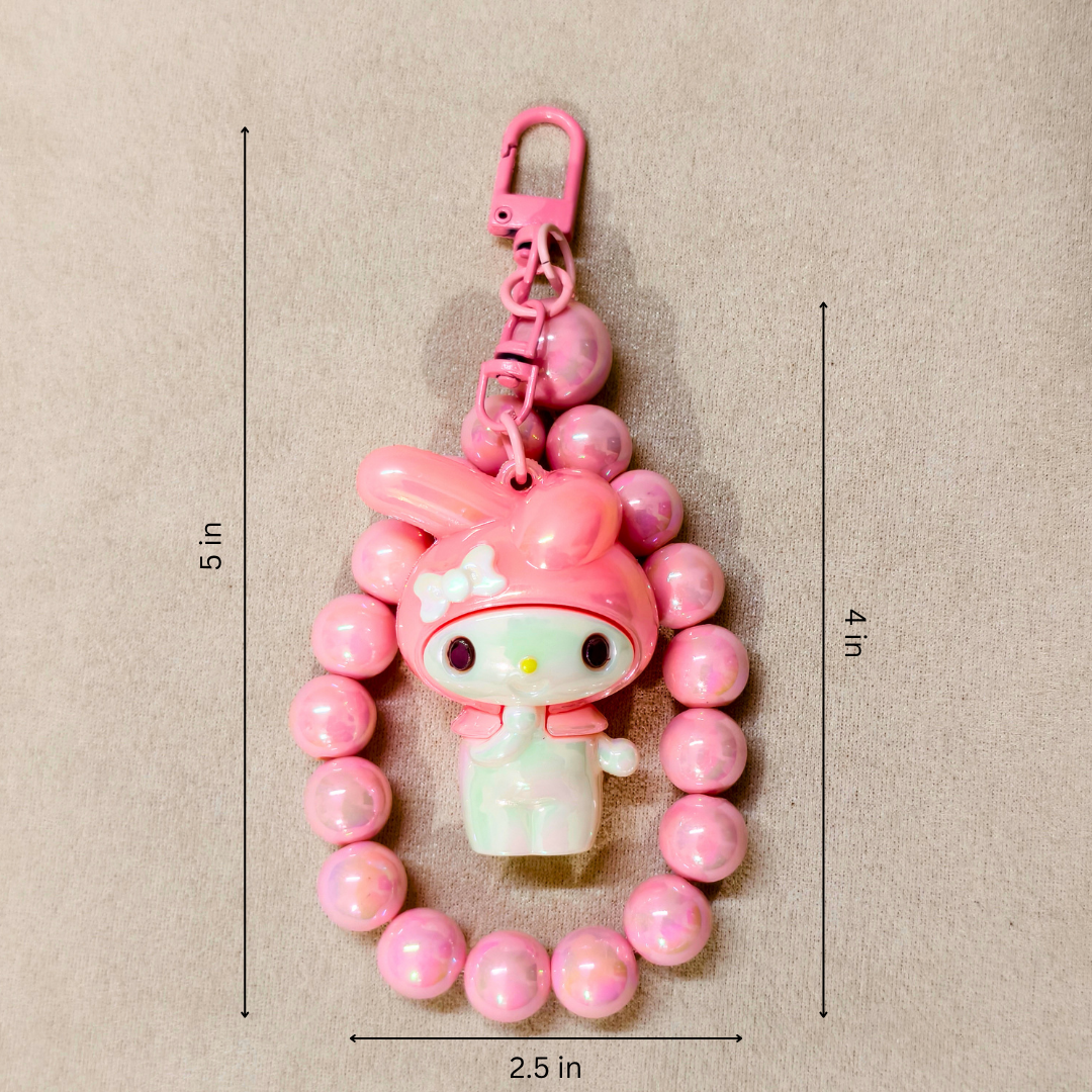 Pink character keychain with measurements on a beige background