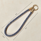 Keychain with blue rope and gold clasp on a beige background