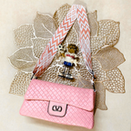 Pink handbag with a decorative strap on a textured beige background