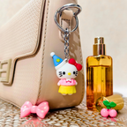 Hello Kitty keychain attached to a beige handbag with a bottle of perfume next to it.