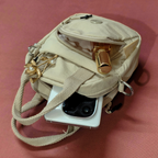 Beige handbag with a camera attached on a pink background