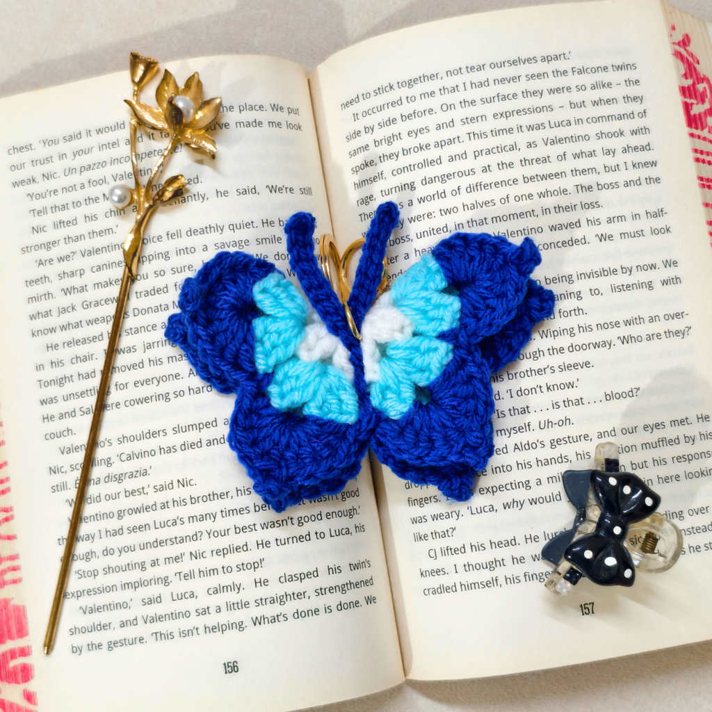 Evil Eye Blue Crochet Key Chain Displayed With Props In The Front Of Beige Background.