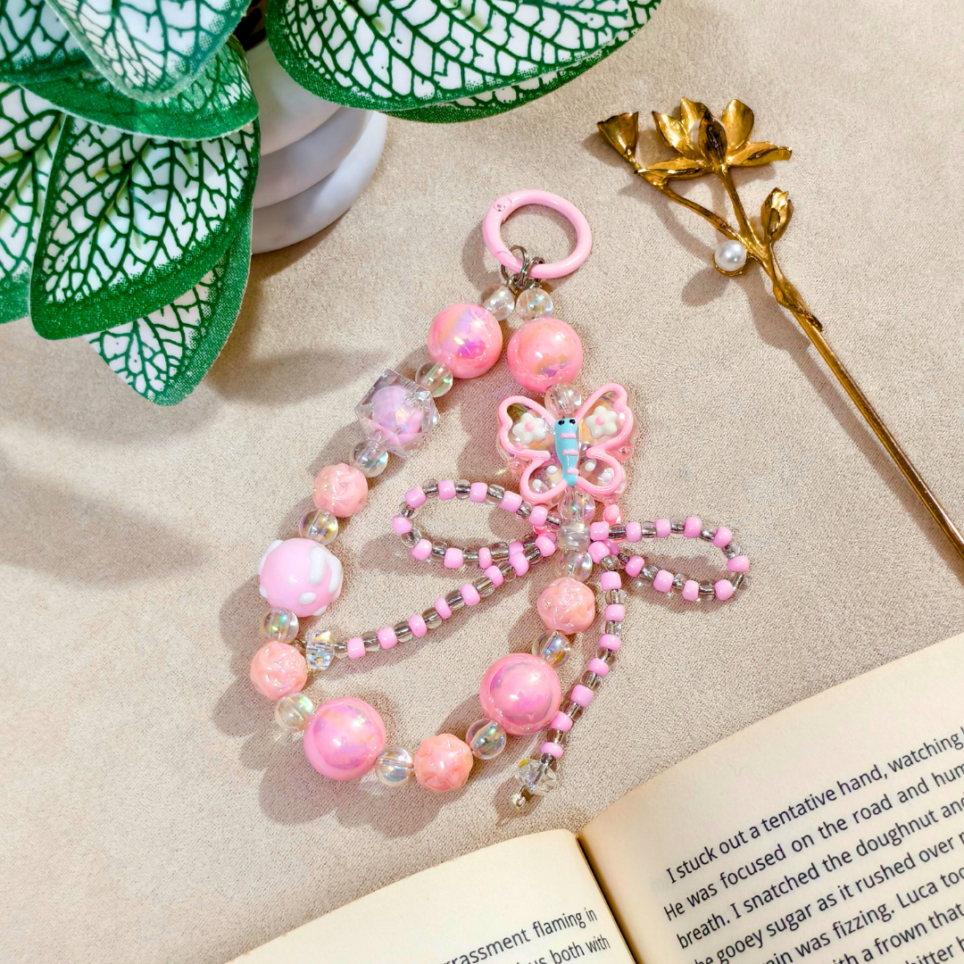 Pink beaded dragonfly charm on a book with decorative elements