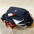 Black bag with sunglasses and a book on a textured surface