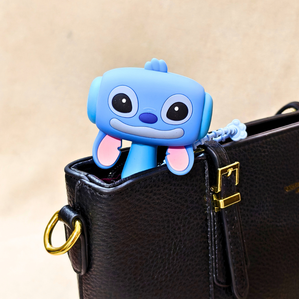 Blue cartoon character keychain attached to a black leather bag with a gold buckle.