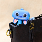 Blue cartoon character keychain attached to a black leather bag with a gold buckle.