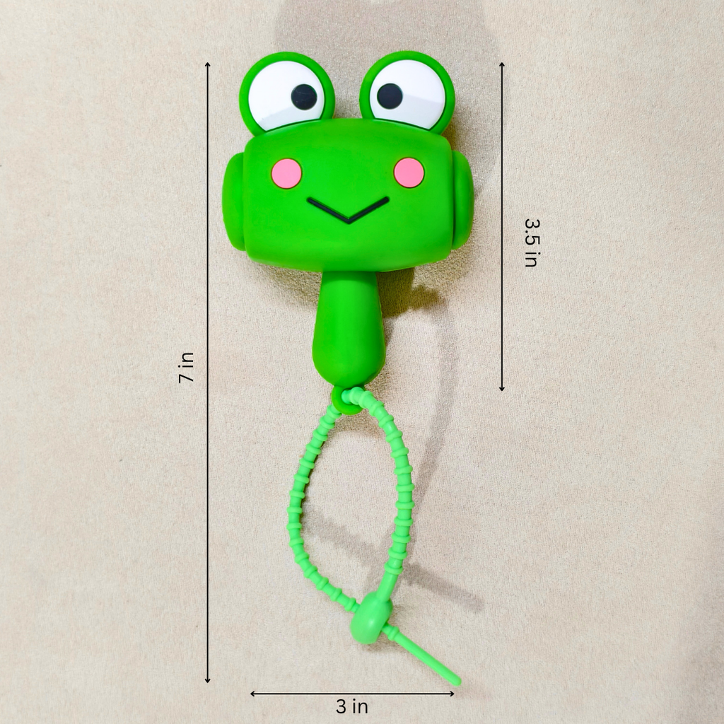 A green frog-shaped wall hook with a coiled cord and a pull tab, shown on a beige background with dimension lines and text indicating 7 in height, 3.5 in ear-to-ear width, and 3 in cord width.
