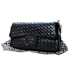 Black quilted handbag with a strap on a white background
